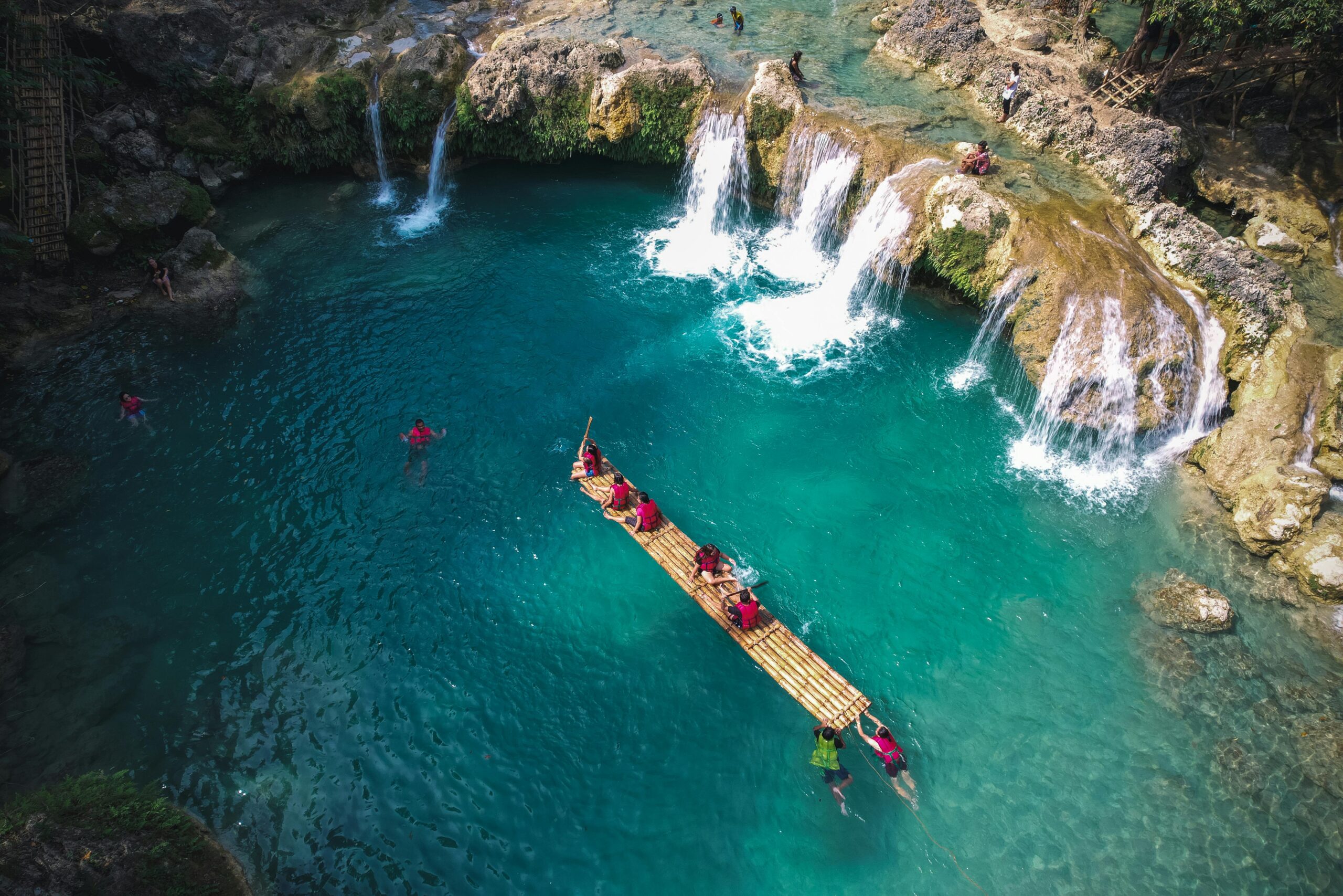 Stunning aerial shot of tourists rafting in the turquoise waters of Bolinao's blue lagoon with waterfalls.