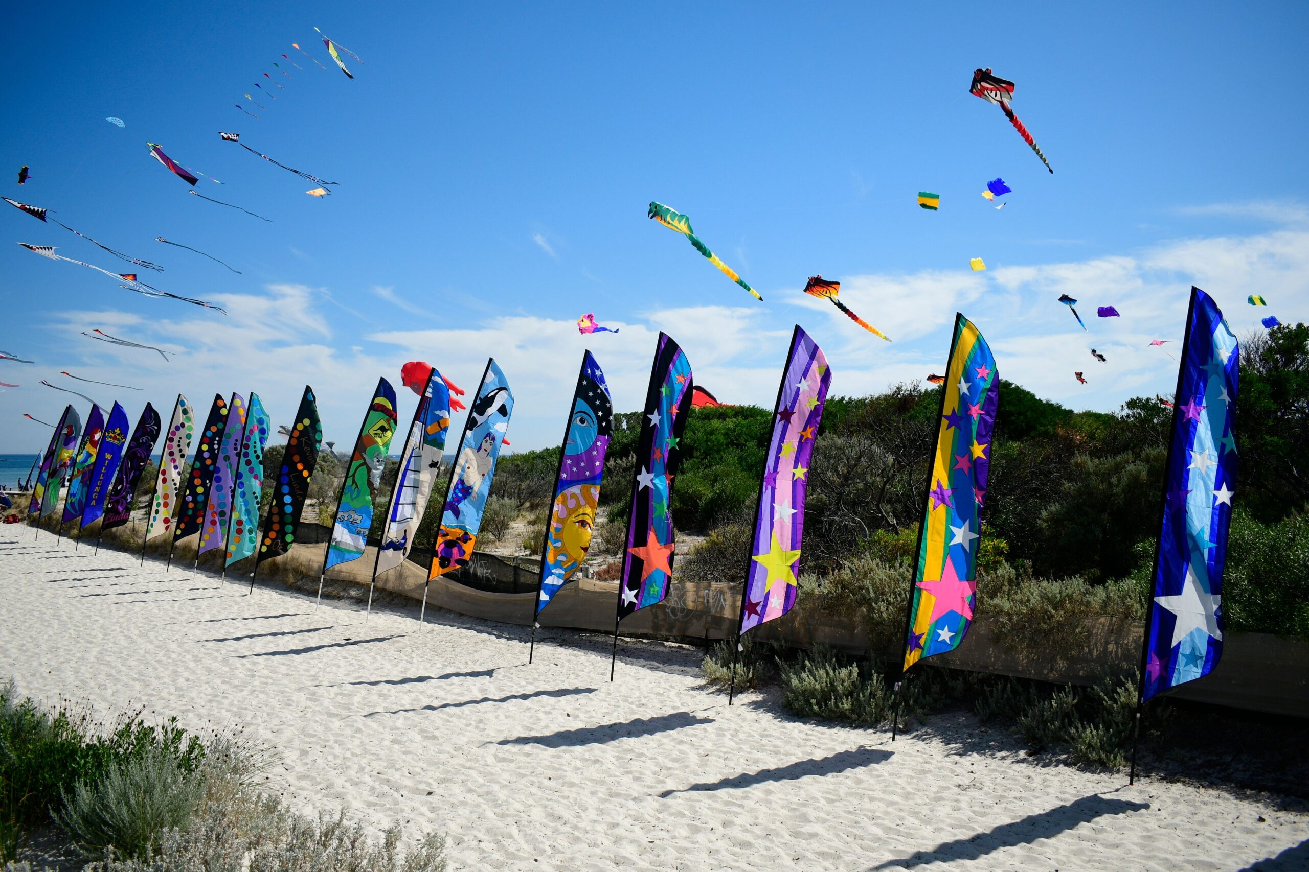 Colorful kites soar over Semaphore Beach festival in South Australia, showcasing art and summer fun.