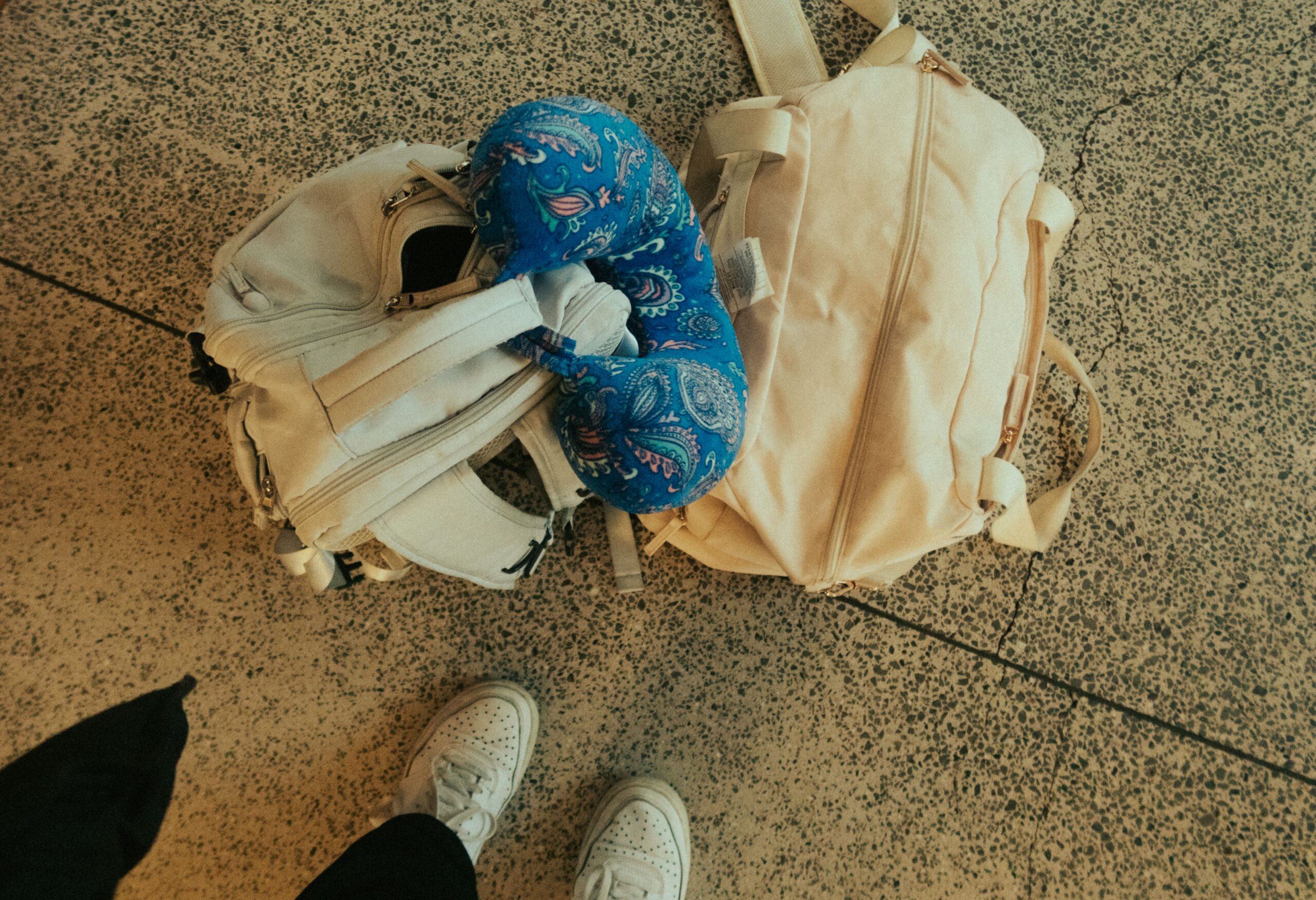 Top view of luggage, backpack, and neck pillow at airport, ready for travel.